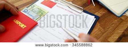 Male Hand Hold Silver Pen With Passport. Filling China Apllication Form Concept