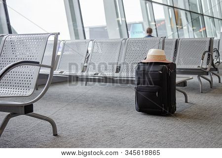 Suitcase In An Airport Waiting Area, One Black Suitcase In An Airport Waiting Room.