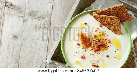 Creamy Cauliflower Soup In A Bowl On A Wooden Table