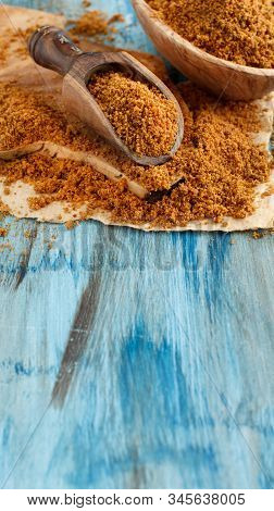 Brown Unrefined Cane Sugar On A Blue Wooden Table Close Up