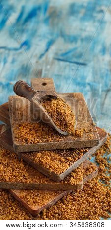 Brown Unrefined Cane Sugar With A Spoon On A Blue Wooden Table