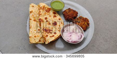 Hydrabadi Kawab Paratha With Green Chili Sauce & Onion On Transparent Plate. Kabab An Irani Dish Wit