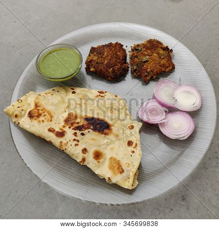 Hydrabadi Kawab Paratha With Green Chili Sauce & Onion On Transparent Plate. Kabab An Irani Dish Wit