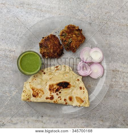 Hydrabadi Kawab Paratha With Green Chili Sauce & Onion On Transparent Plate. Kabab An Irani Dish Wit