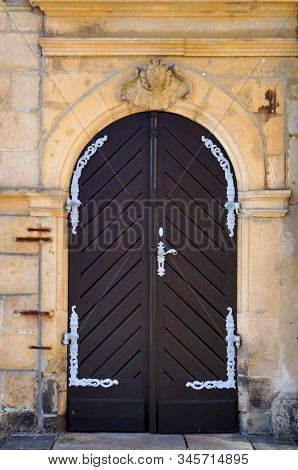 Wooden door with round part at top. Sculptural bas-relief of angel above the door. Entrance in ancient building in Celle, Germany. 