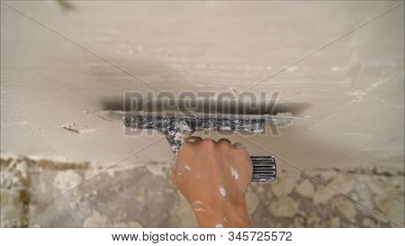 Construction Notched Trowel And Worker Hands With White Mortar On Wall. Worker Levels A Wall With Mo