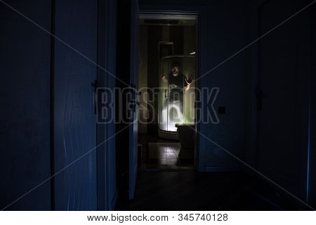 Horror Silhouette Of Person In Window. Scary Halloween Concept Blurred Silhouette Of Witch In Bathro