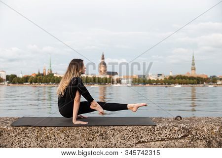 Yoga Meditation And Wellness Lifestyle Concept. Fit Slim Woman Practicing Yoga Exercises Near River 