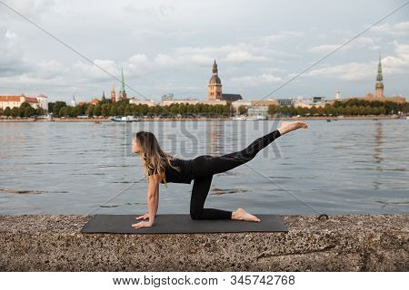 Yoga Meditation And Wellness Lifestyle Concept. Fit Slim Woman Practicing Yoga Exercises Near River 