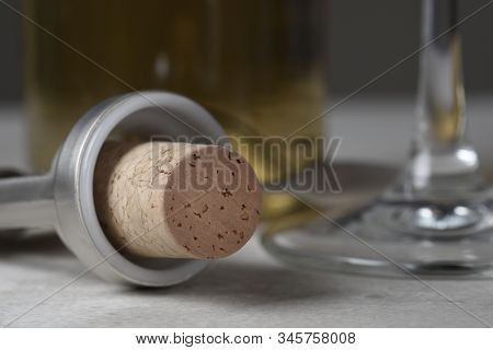 Closeuup of a wine cork in wing style corkscrew with glass and bottle in background.  Shallow depth of field. 