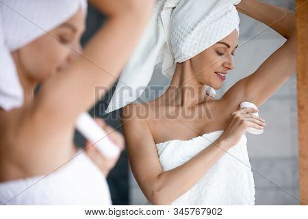 Smiling Beautiful Woman Applying Antiperspirant To Armpit In Bathroom