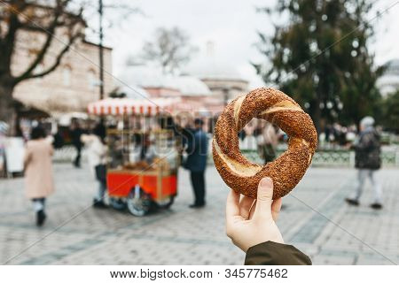 A Person Is Holding A Traditional Turkish Bagel Simit On The Background Of A Street Stall Selling Si