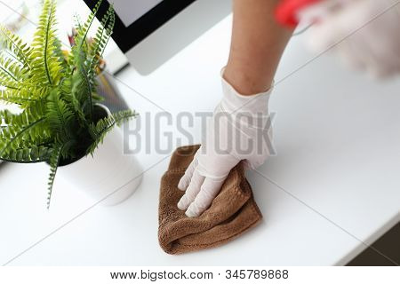 Close-up Of Person Hand In Glove Holding Brown Fluffy Cloth And Swiping Dust From White Office Compu