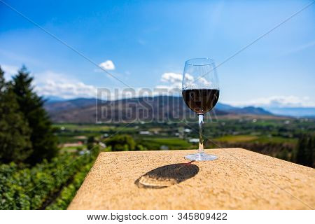 A Canadian Glass Of Red Wine On A Building Top Selective Focus View Against Vineyard Fields Backgrou