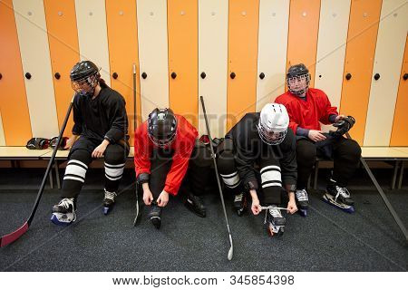 High Angle View At Female Hockey Team Putting On Gear In Locker Room While Preparing For Match Or Pr