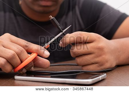 Hands Cutting The Micro Usb Charging And Data Cable Or Cord With Scissor.