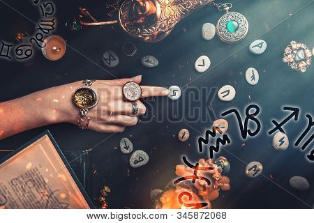 Astrology And Esotericism. The Witchs Female Hands Point To The Runestone. On A Black Background Lie