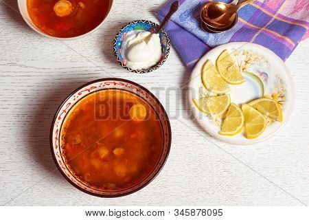 Top Horizontal View Of Hodgepodge Soup Made Of Various Ingredients Serving With Sour Cream And Lemon