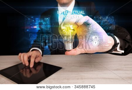 Businessman holding lightbulb with INTELLECTUAL PROPERTY inscription, online security idea concept