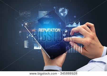 Businessman holding a foldable smartphone with REPUTATION inscription, successful business concept
