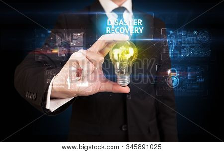 Businessman holding lightbulb with DISASTER RECOVERY inscription, online security idea concept