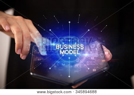 Businessman holding a foldable smartphone with BUSINESS MODEL inscription, new business concept