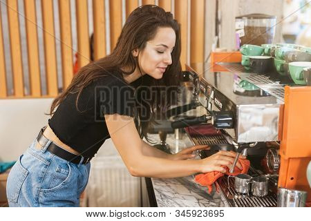 Young Smiling Barista Woman Wiping Professional Coffee Machine With Dust , Barist Work Routine