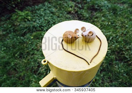 Two Wooden Mice Couple Sitting On A Metal Yellow Round Cylinder