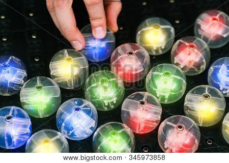 A Mans Hand Inserts A Lamp Into An Electrical Panel. Colored Light Bulbs On A Black Panel. Radio Ele
