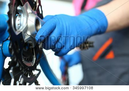 Close-up Of Man Mechanic Hand In Gloves Examines And Fixes Modern Cycle Transmission System. Skilled