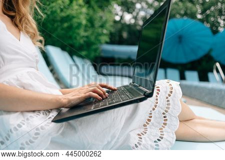 Remote Work Of A Female Freelancer Or Businesswoman Working On A Laptop Near The Pool. Close-up Of A