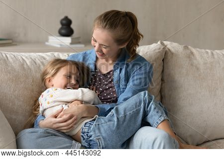 Affectionate Millennial Mother Tickling Laughing Small Daughter.