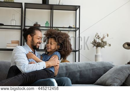 Happy Cheerful Black Dad Cuddling, Tickling Playful Excited Daughter