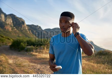 Black Young Adult Male Putting His Wireless Earphone In. Getting Ready To Train On The Beautiful Mou