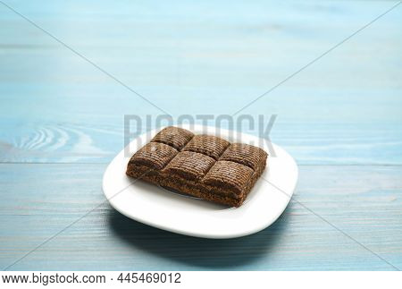 White Plate With Delicious And Healthy Hematogen Bar  On Blue Wooden Table. Space For Text