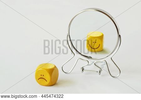 Yellow Dice With Sad Expression Looking In The Mirror And Seeing Himself Smiling - Concept Of Person