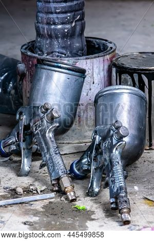 Two Metal Industrial Paint Spray Gun With The Can Behind For Paintwork Garage Background