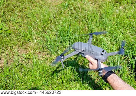 Man Holding A Drone Before Flying With Green Grass On The Background.