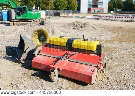 Street Sweeper Machine  On Construction Site. Green Exavator In Background.