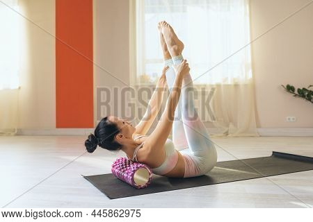 A Woman Performs Myofascial Relaxation Of Hyper-flexible Muscles Of The Back Using A Massage Roller 