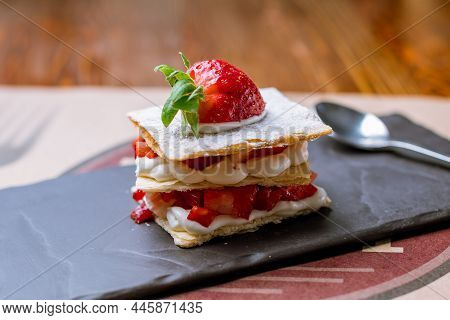 Millefeuille With Strawberries On Black Stone On Wooden Table