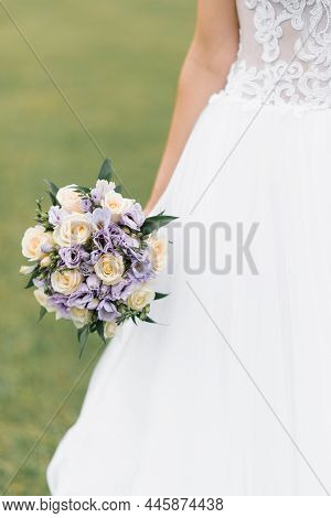 The Bride's Wedding Bouquet Of Milk Roses And Lilac Eustoms In The Hands Of The Bride Close-up