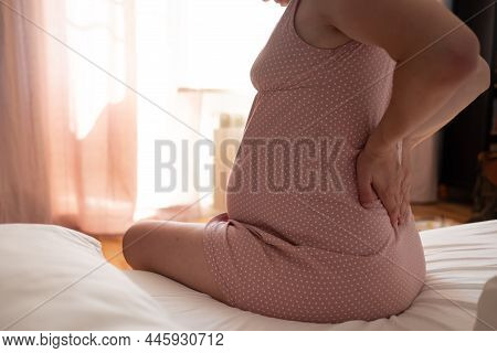 Woman Suffering From Pains At Home, Sitting At Bed, Touching Her Tummy And Back, Expecting Lady Havi