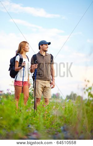 Couple of smiling trippers standing in the countryside at summer