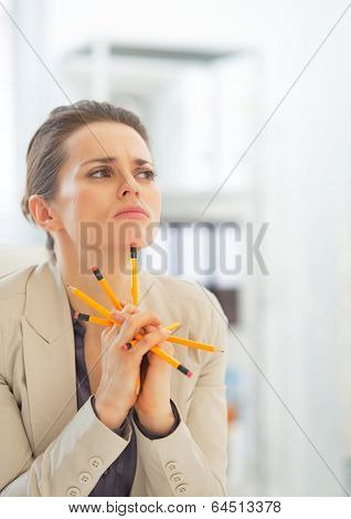 Portrait Of Thoughtful Business Woman Holding Pencils