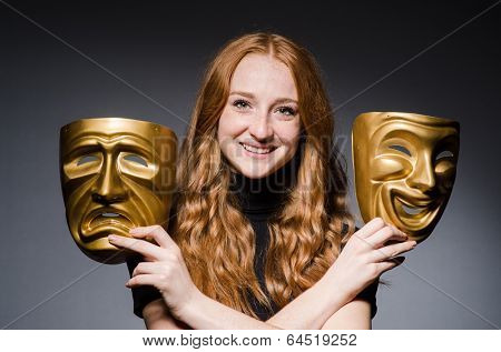 Redhead woman iwith masks in hypocrisy consept against grey background