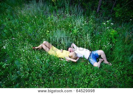 Loving Couple Lying On Green Grass In Summer