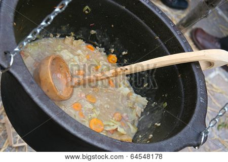 Making of a soup in old kettle with wodden ladle