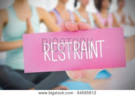 Woman holding pink card saying restraint against fitness class in gym