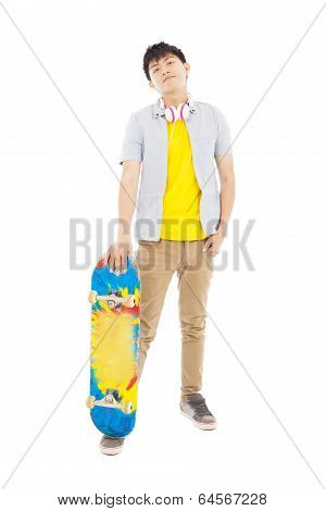 Full Length Of A Young Man Standing And Holding A Skateboard